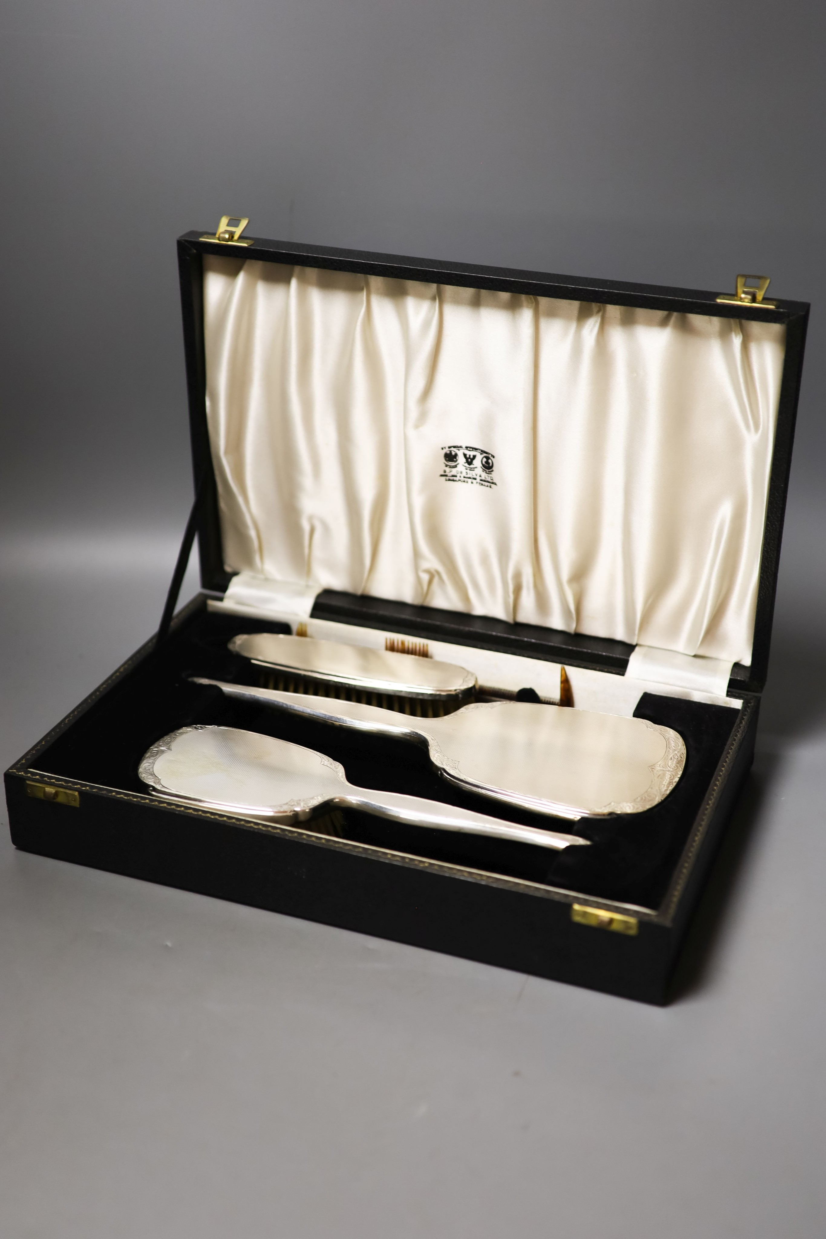 A modern cased engine turned silver three piece brush set.